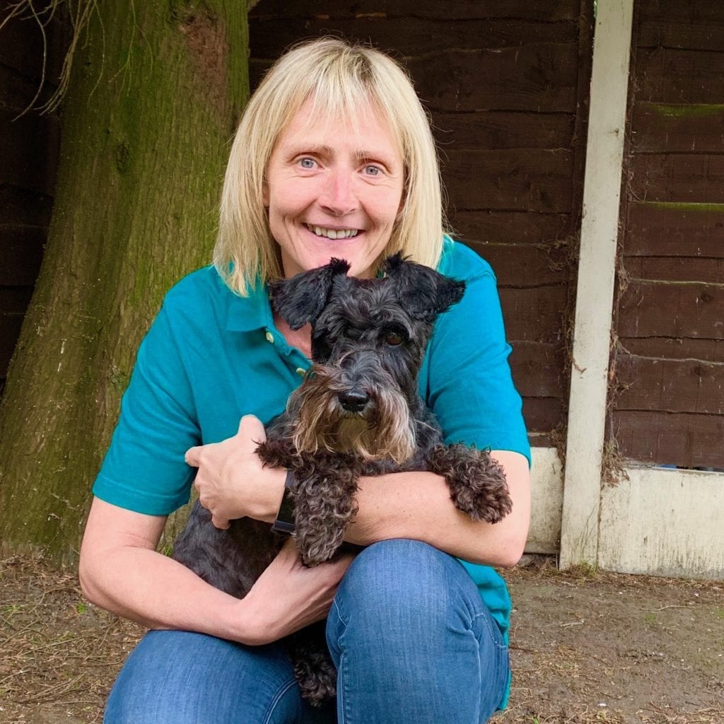 Paula cuddling her dog and smiling
