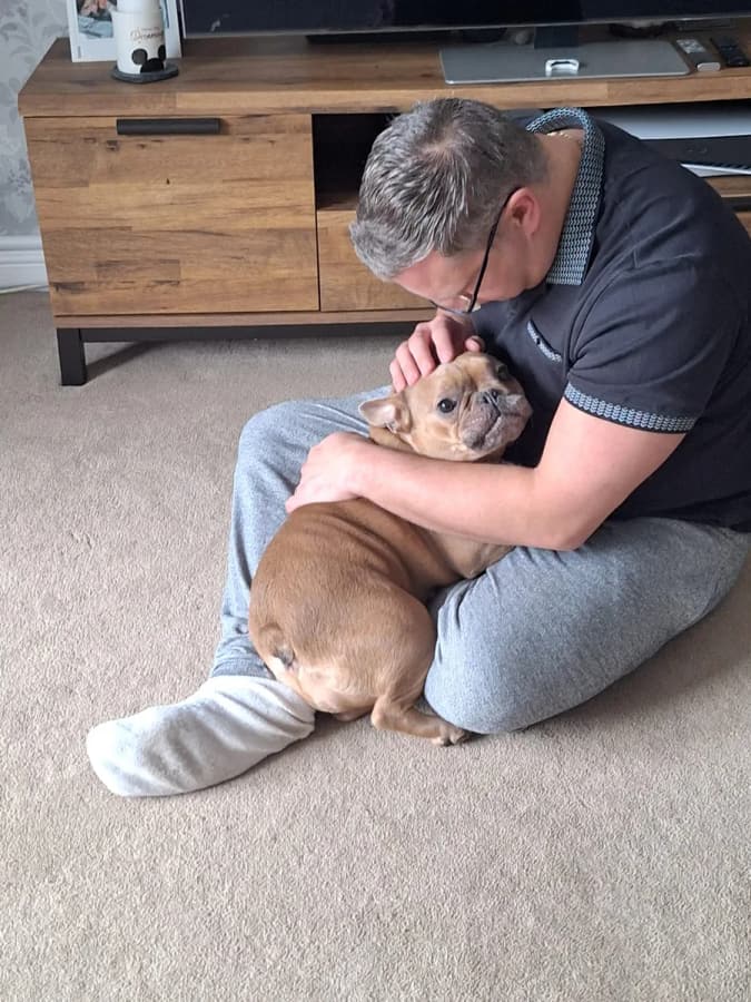 A home boarder cuddling a small dog on his lap
